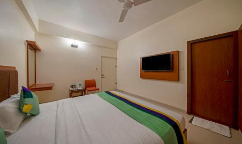 a bedroom with a bed and a tv on the wall at Treebo Sam Residency in Coimbatore