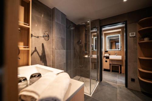 ein Bad mit einem Waschbecken und einer Dusche in der Unterkunft Kulmberghaus Resort in Saalfeld