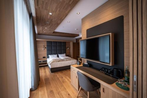 a bedroom with a bed and a desk with a television at Kulmberghaus Resort in Saalfeld