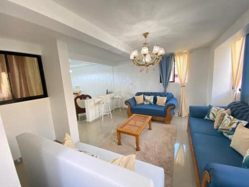 una sala de estar con muebles azules y una lámpara de araña. en Elegant 3 bed apartment in Santiago DR, en Santiago de los Caballeros