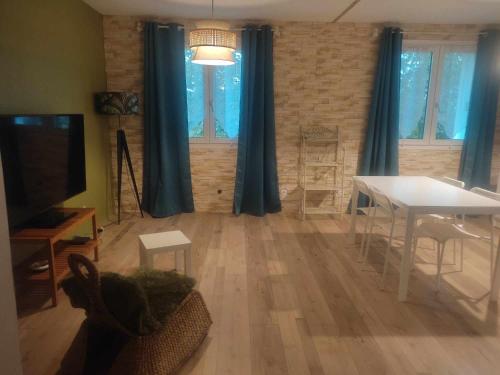 sala de estar con cortinas azules, mesa y TV en Jad'Iss, en LʼIsle-dʼAbeau