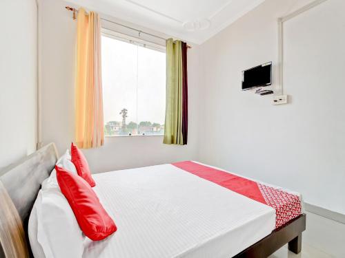 a bedroom with a bed with red pillows and a window at Collection O Sangam Hotel in Chirāwa