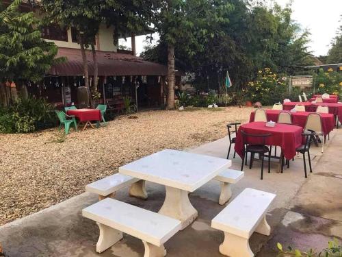 a group of picnic tables and chairs with red tables and chairs at Good View Nan Restaurant & hotel in Nan