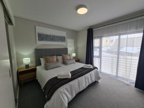 a bedroom with a bed and a large window at 116 The Esplanade in Hermanus