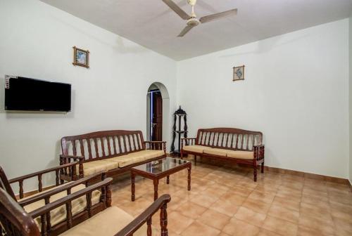 sala de estar con 2 sofás y TV de pantalla plana en Super OYO Pravin Holiday Homes, en Calangute