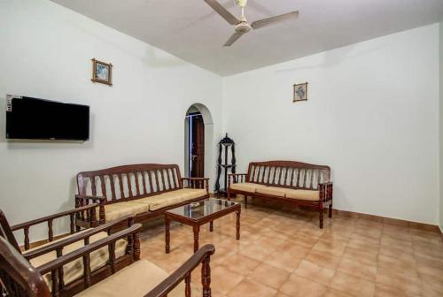 uma sala de estar com bancos e uma televisão de ecrã plano em Super OYO Pravin Holiday Homes em Calangute