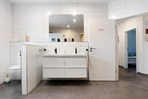 a white bathroom with a sink and a toilet at Speicherhäuschen Maren in Geeste