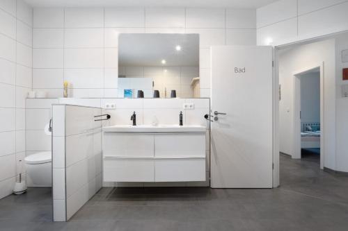 a white bathroom with a sink and a toilet at Speicherhäuschen Maike in Geeste