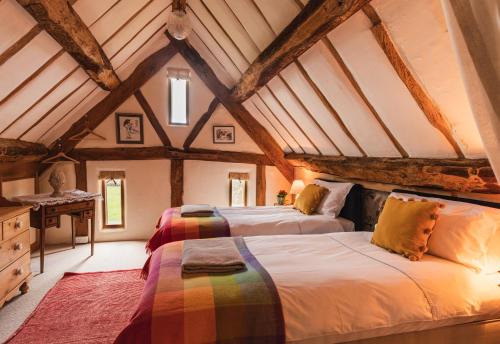 two beds in a attic room with wooden ceilings at Meadow End Barn in Dorstone