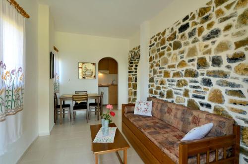 a living room with a couch and a stone wall at Albatros Studios & Apartments in Plakias