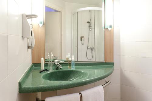 baño con lavabo verde y espejo en Ibis Bilbao Barakaldo en Barakaldo