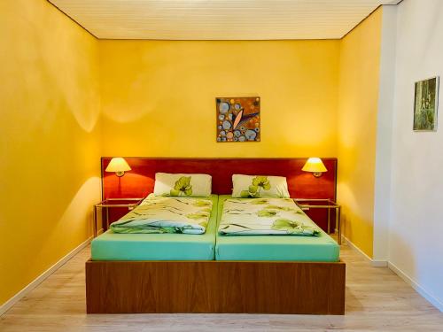 Cama en habitación con pared amarilla en Ferienwohnungen Deidesheim en Deidesheim