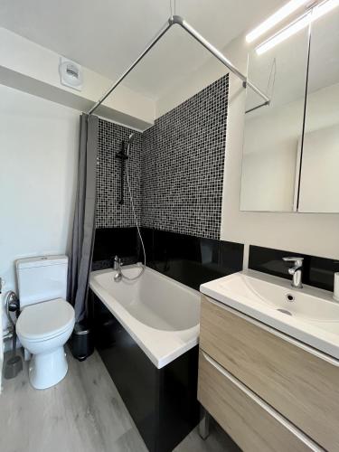 une salle de bain avec toilettes, lavabo et baignoire dans l'établissement Studio moderne en bord de mer, à Cabourg