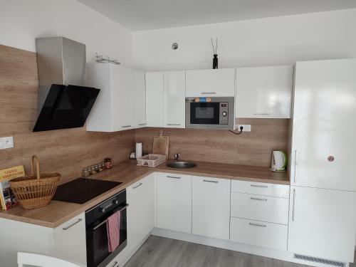 a white kitchen with white cabinets and a microwave at APARTMÁN ČAMBOR - na skok do prírody a mesta in Stupava