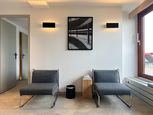 two chairs in a waiting room with a picture on the wall at La Cachette, Friendly Hotel & Spa in Arc 1600