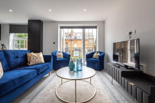 ein Wohnzimmer mit einem blauen Sofa und einem Tisch in der Unterkunft LUXURIOUS Apartments FREE parking and FREE WiFi! in Staines