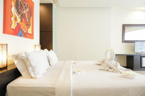 1 dormitorio con 1 cama con sábanas blancas y almohadas blancas en Sunset Mansion Seminyak, en Seminyak