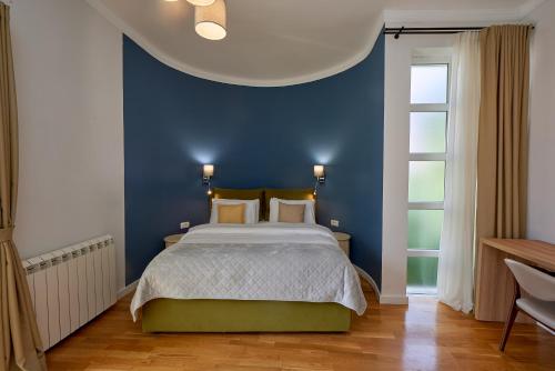 a bedroom with a blue wall and a bed at 2montenegro MIMOZA Apartments in Dobrota