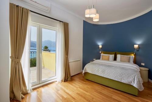 Dormitorio azul con cama y ventana grande en 2montenegro MIMOZA Apartments en Dobrota