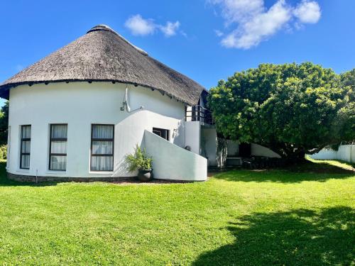 a large white building with a thatched roof at Anchor Drift in St Francis Bay