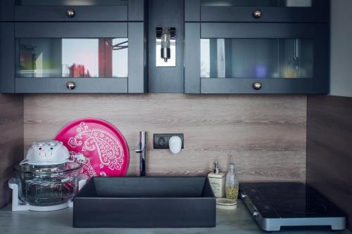 a kitchen with black cabinets and a pink plate at Lelle Marine Resort Voila Apartman in Balatonlelle