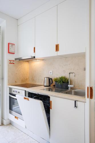 a kitchen with white cabinets and a sink at Lisbon Sunny Terrace Lapa Santos in Lisbon