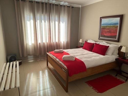 a bedroom with a large bed with red pillows at 19 Richthofen in Swakopmund