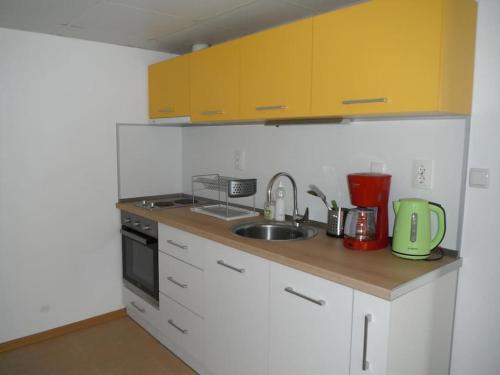 a kitchen with yellow cabinets and a sink at Gradina Apartment in Montana