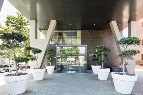 a group of potted trees in front of a building at Hotel Best 4 Barcelona in Barcelona