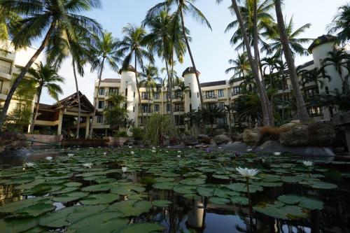a pond with lilies in front of a building with palm trees at Tanjung Rhu Resort in Tanjung Rhu 