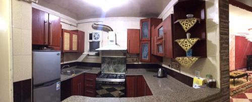 uma cozinha com armários de madeira e um frigorífico de aço inoxidável em شقة مفروشة no Cairo