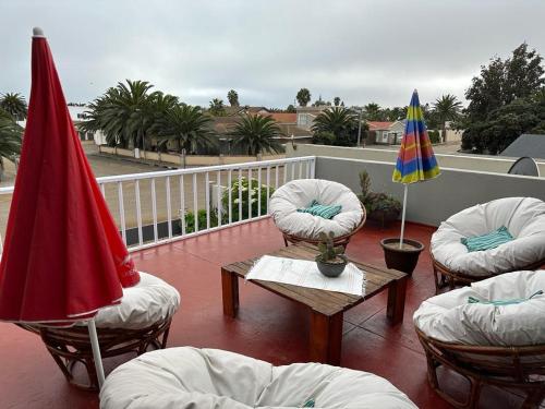 a balcony with chairs and a table and umbrellas at 19 Richthofen in Swakopmund