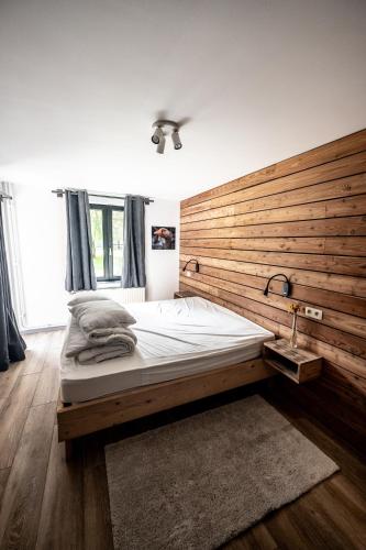 a bedroom with a large bed with a wooden wall at L'arche De Noé in Dinant