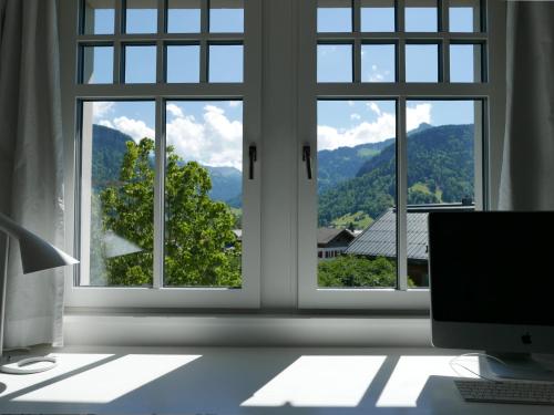 una oficina con 3 ventanas con vistas a las montañas en Boutique Apartments Bezau, en Bezau