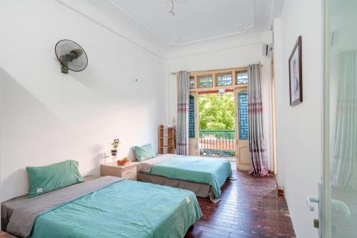 two beds in a room with a window at Ha Noi Homestay in Hanoi