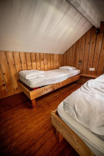 two beds in a room with wooden walls at L'arche De Noé in Dinant