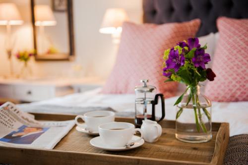 ein Tablett mit Tassen und eine Vase mit Blumen auf dem Bett in der Unterkunft The White Hart, Overton in Overton