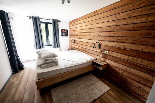 a bed in a room with a wooden wall at L'arche De Noé in Dinant