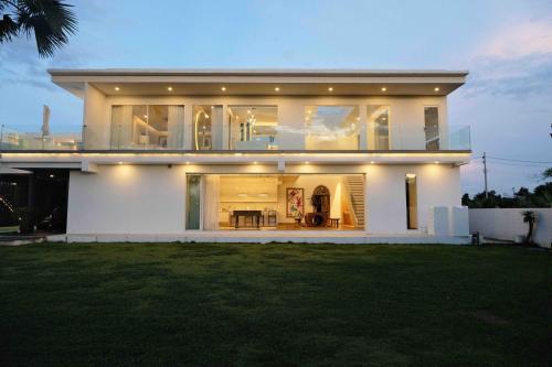 Cette grande maison blanche dispose d'une grande fenêtre. dans l'établissement Palm Villa - Award Winning Modern Luxury & Exclusive Villa Resort, à Chiang Mai
