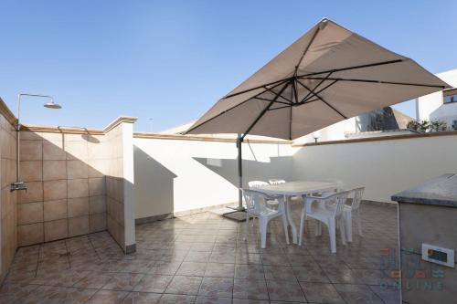 Casa vacanza Lucia Puglia On line في مورتشانو دي ليوكا: طاولة وكراسي مع مظلة على الفناء
