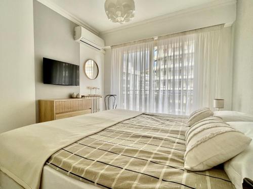 une chambre avec un grand lit et une fenêtre dans l'établissement Palais Lumière, à Cannes