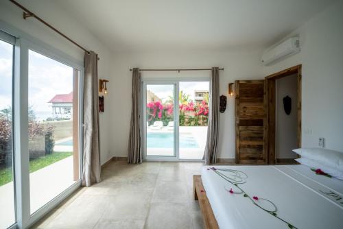 SandBank View Villa - Private Pool- ZanzibarHouses في كيوينجوا: غرفة نوم بسرير وباب زجاجي منزلق كبير