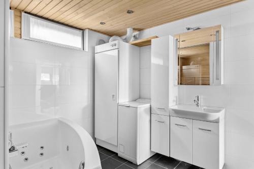 uma casa de banho branca com um lavatório, uma banheira e um espelho. em Happy Home Lauttasaari em Helsinque
