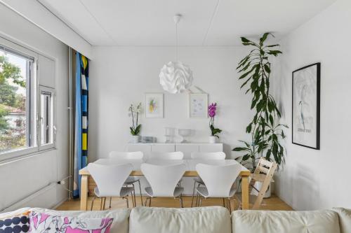 a living room with a table and white chairs at Happy Home Lauttasaari in Helsinki