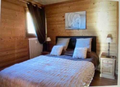 sypialnia z łóżkiem z drewnianą ścianą w obiekcie Appartement l'Edelweiss w mieście Megève