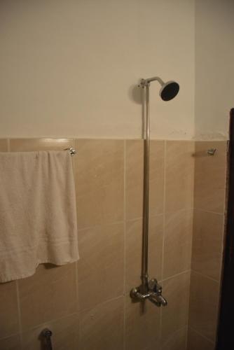 a shower with a shower head and a towel at Sardar House, Dunga Gali in Dunga Gali