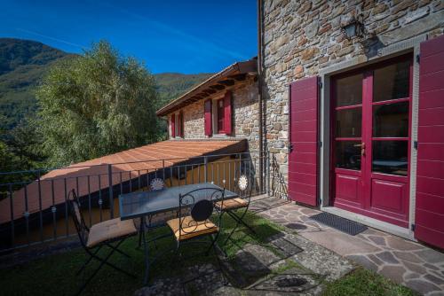 a house with red doors and a table on a balcony at La Vecchia Fornace La Piastra Apartments shared pool- Abetone in Cutigliano