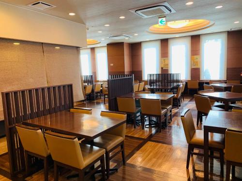 a dining room with wooden tables and chairs at Hotel Route-Inn Sendaiko Kita Inter in Tagajo