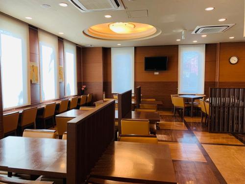 a conference room with tables and chairs and a tv at Hotel Route-Inn Sendaiko Kita Inter in Tagajo