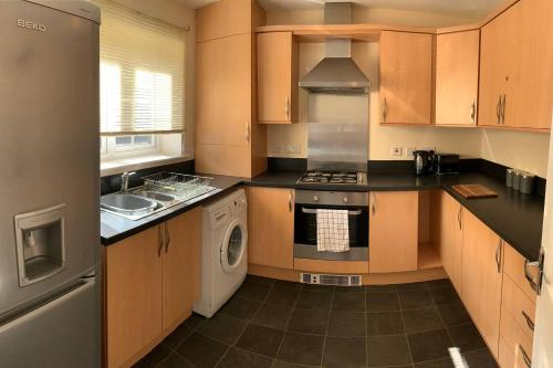 a kitchen with a stove and a washer and dryer at Aidan House by Blue Skies Stays in Middlesbrough